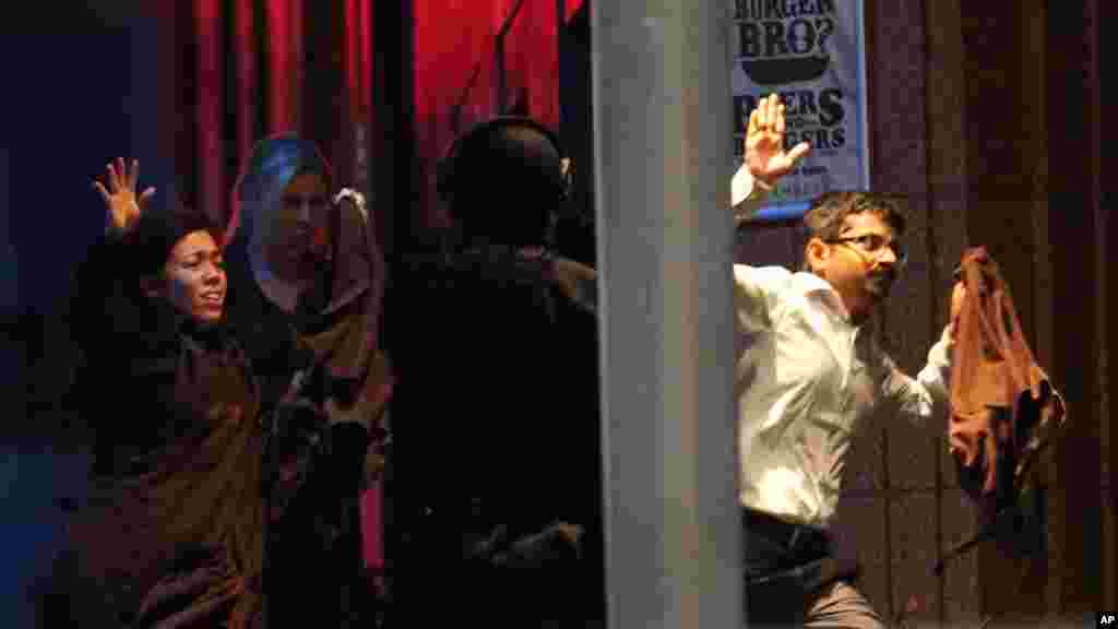 Hostages run towards armed tactical response police as they run to freedom from a cafe under siege at Martin Place in the central business district of Sydney, Australia, Dec. 16, 2014.