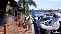 Des responsables ougandai de la santé portant un équipement de protection désinfectent le marché en plein air de Nakawa dans le cadre de mesures de prévention de la propagation du coronavirus à Kampala, le 17 avril 2020.