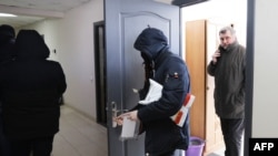 Kepala Asosiasi Jurnalis Belarusia (BAJ) Andrei Bastunets (kanan) dan polisi Belarusia meninggalkan kantor BAJ setelah penggerebekan di Minsk, Belarusia, 16 Februari 2021.