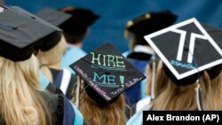 Graduates, including one looking for a job, are seated during George Washington University's commencement exercises on the National Mall, Sunday, May 17, 2015 in Washington, DC.