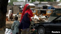 Wata mata da 'ya'yanta biyu a dab da tashar motar titin Jos a Maiduguri tana jiran shiga mota. 