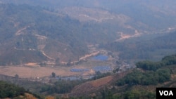 位于中缅边境大山里的克钦难民营（蓝色屋顶）。从中国境内一侧拍摄。（美国之音朱诺拍摄，2015年3月16日）