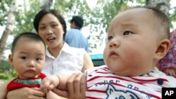 Deux bébés chinois avec leur mère dans un parc de Pékin, le 10 juillet 2003. (AP Photo/Greg Baker) 