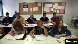 ARCHIVO - Víctor Antúa, de España, (arriba a la der.) y Felipe Barbosa, de Colombia, (segundo de la der.) asisten a clases de inglés en el Centro de Educación para Adultos en Madrid.