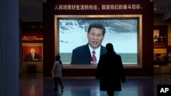 FILE - Chinese President Xi Jinping is seen on screen near the slogan "The people's yearning for a better life is the goal we strive for" at the Museum of the Communist Party of China in Beijing, China, Nov. 12, 2021. 