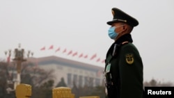 A paramilitary police officer stands guard near the Great Hall of the People before the opening session of the National People's Congress (NPC) in Beijing, China, March 5, 2021. 