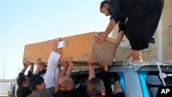 Un cercueil est chargé sur un véhicule avant un enterrement, à Bassora, en Irak le 26 septembre 2018. (AP Photo/Nabil al-Jurani)