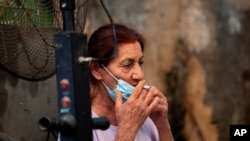 Una mujer israelí baja su mascarilla para fumar un cigarrillo en un mercado del pueblo de Rambla, cerca de Tel Aviv, el pasado 15 de julio.