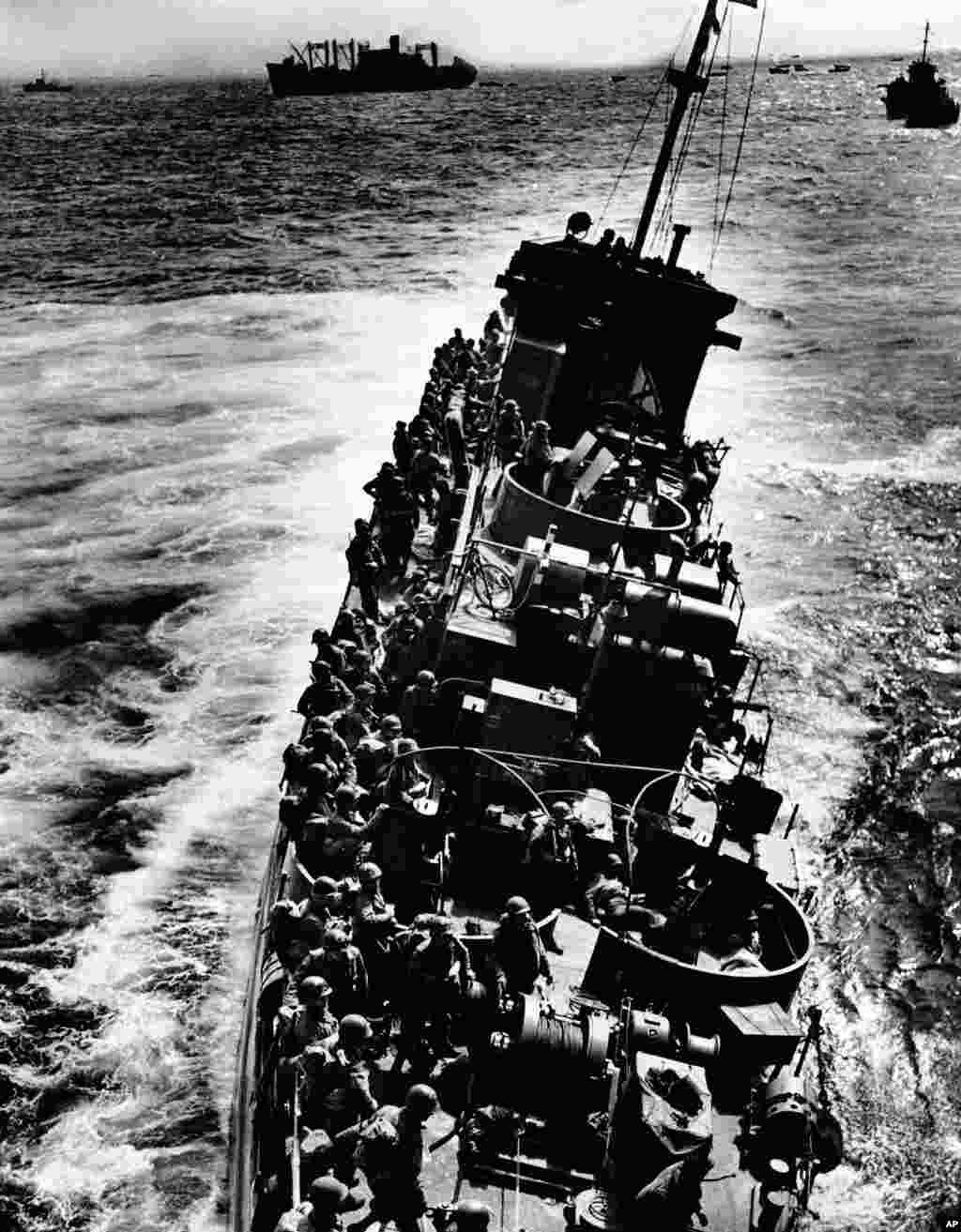 A Coast Guard LCI, listing to port, pulls alongside a transport ship to evacuate the troops and wounded just before the craft capsized and sank during the invasion of Normandy, France, June 6, 1944. 