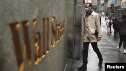 Archivo - Un hombre usando una máscara protectora camina en Wall Street el 13 de marzo de 2020.