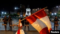 Archivo - Las fuerzas de seguridad hacen guardia mientras un manifestante ondea la bandera de Perú durante una protesta para exigir la disolución del Congreso y elecciones democráticas, rechazando a Dina Boluarte como presidenta de Perú, el 12 de enero de 2023.
