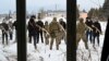 A military instructor teaches civilians holding wooden replicas of Kalashnikov rifles, during a training session at an abandoned factory in the Ukrainian capital of Kyiv on Jan. 30, 2022.