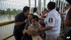Une mère migrante du Honduras et son fils traversent le pont après avoir franchi la frontière entre le Guatemala et le Mexique, à Ciudad Hidalgo, au Mexique, le samedi 20 octobre 2018. 