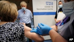 PM Inggris Boris Johnson menyaksikan vaksinasi massal dengan vaksin COVID-19 produksi Pfizer-BioNTech di London, Selasa (8/12). 