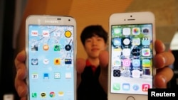 FILE - Sales associate displays Samsung Electronics' Galaxy 5 smartphone, left, and Apple Inc.'s iPhone 5 in Seoul, July 16, 2014.