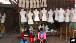 FILE - Women sit in front of mannequins at a textile market shuttered due to the coronavirus pandemic, in Jakarta, Indonesia, April 30, 2020.