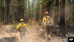 Los bomberos Garret Suza, a la derecha, y Cameron Taylor, del Servicio Forestal de Chiloquín, buscan puntos calientes en el lado noreste del Bootleg Fire, el miércoles 14 de julio de 2021, cerca del río Sprague, Oregon (Foto AP / Nathan Howard)