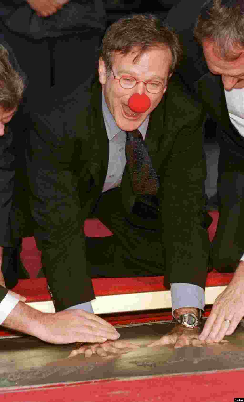 Aktor pemenang Academy Award Robin Williams, mengenakan prop dari film barunya "Patch Adams" meletakkan tangannya di semen dalam upacara penghormatan baginya di Mann's Chinese Theater, di Hollywood, 22 Desember 1998.