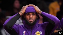Penyerang Los Angeles Lakers, LeBron James, duduk di bangku cadangan selama paruh pertama pertandingan basket NBA pramusim melawan Golden State Warriors, 14 Oktober 2019, di Los Angeles. (Foto: AP)