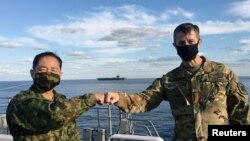 駐日美軍司令施耐德（右）與日本自衛隊參謀長山崎幸二在日本加賀號護衛艦上見面，背景是美國海軍裡根號航母。(2020年10月26日)