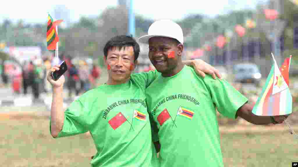 An unidentfied Chinese national and a Zimbabwean man hug while welcoming Chinese President Xi Jinping upon his arrival in Harare, Zimbabwe, Tuesday, Dec. 1. 2015. Jinping is in Zimbabwe for a two day State visit during which he is set to sign some bilateral agreements aimed at strengthening relationships between the two countries.