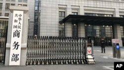 A man checks his mobile phone near the main entrance of the Ministry of Commerce in Beijing, Jan. 9, 2019. U.S. and Chinese negotiators extended trade talks into a previously unscheduled third day Wednesday.