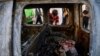 Palestinian kids look at a destroyed car after it was hit in an Israeli airstrike, in Gaza City, May 19, 2021.