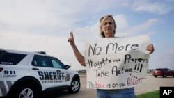 Mary Ann Foley sostiene un cartel de protesta frente a una vigilia de oración luego de un tiroteo masivo el día anterior, el domingo 7 de mayo de 2023, en Allen, Texas. (Foto AP/LM Otero)