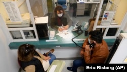 Mohammad Attaie dan istrinya Deena, yang baru tiba dari Afghanistan, mendapatkan bantuan dari penerjemah medis Jahannaz Afshar membuat janji untuk bertemu dokter di Program TB/Pengungsi Valley Health Center di San Jose, California, 9 Desember 2021. (AP/Eric Risberg)