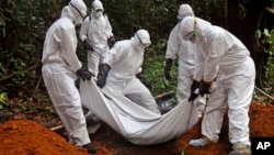 Health workers bury the body of a woman who is suspected of having died of the Ebola virus in Bomi county, on the outskirts of Monrovia, Liberia, Monday, Oct. 20, 2014. Liberian President Ellen Johnson Sirleaf said Ebola has killed more than 2,000 people in her country and has brought it to "a standstill," noting that Liberia and two other badly hit countries were already weakened by years of war. (AP Photo/Abbas Dulleh)