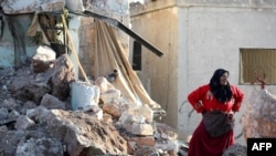 A woman stands amid the rubble of a building that was reportedly destroyed during air strikes by the Syrian regime ally Russia, in the town of Kafranbel in the rebel-held part of the Syrian Idlib province, May 20, 2019.