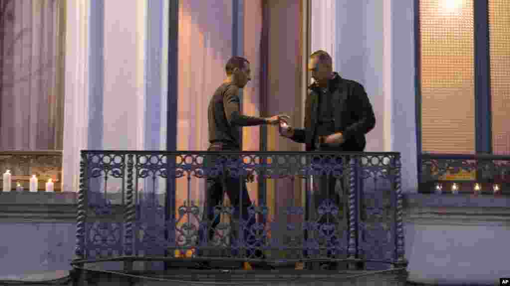 Mohammad Abdeslam, à gauche, frère de Salah et Brahim Abdelslam, auteurs présumés des attaques de Paris, allume des bougies avec un homme non identifié sur le balcon de sa maison de la commune de Molenbeek, Belgique, 18 novembre 2015. 