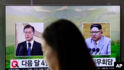 一名女子走过韩国首尔火车站正在播放韩国总统文在寅（左）和朝鲜领导人金正恩画面的电视屏幕。（2018年3月29日）