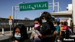 Migrantes de América Central en busca de asilo, que fueron transportados en avión desde Brownsville a El Paso, Texas, y ahí deportados de Estados Unidos, cruzan el puente fronterizo internacional Paso del Norte, en Ciudad Juárez, México, 23 de marzo 2021.