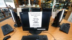FILE - In this Aug. 22, 2019, photo, signs on a bank of computers tell visitors that the machines are not working at the public library in Wilmer, Texas.