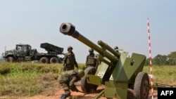 Des soldats des forces armées de la République démocratique du Congo (FARDC) installent une pièce d'artillerie mobile (Front) à côté d'un lance-roquettes multiples mobile à Matombo, à 35 km au nord de Beni, au Nord Kivu, le 13 janvier 2018.