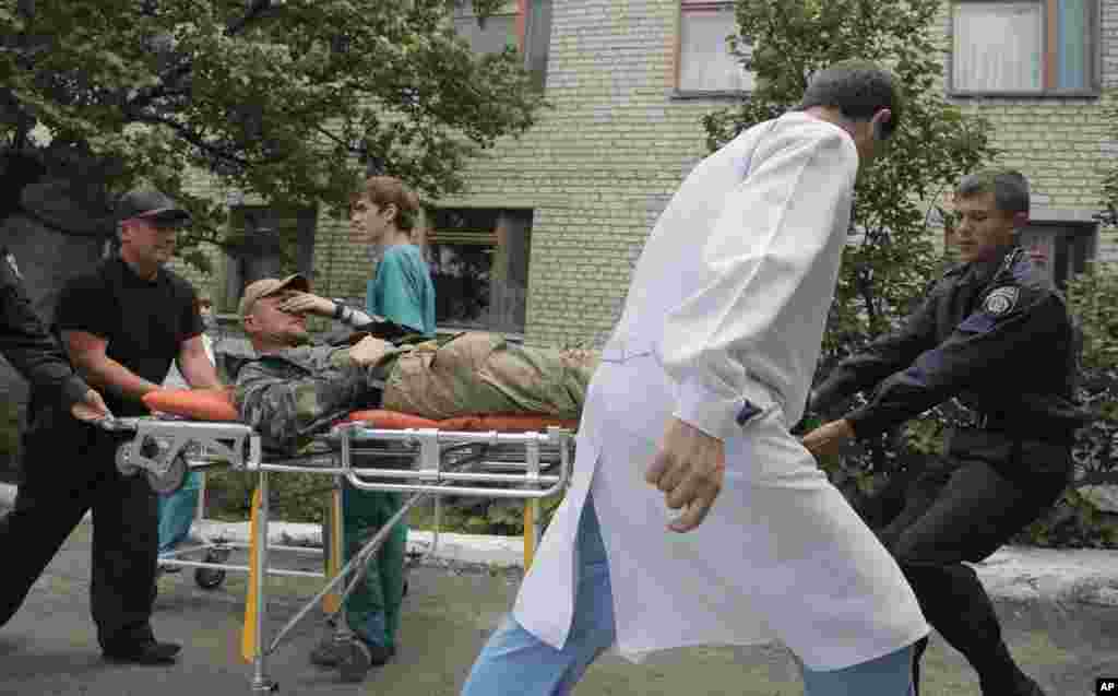 Ukrainalik zobitlar va shifokor yarador harbiyni Slavyansk yaqinidagi kasalxonaga olib kirmoqda, Ukraina, 3-iyun, 2014-yil