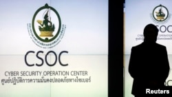 Seorang pria terlihat seperti bayangan saat berada di depan layar Pusat Operasi Keamanan Cyber, CSOC (Cyber Security Operation Center) di Bangkok. (Foto: dok).
