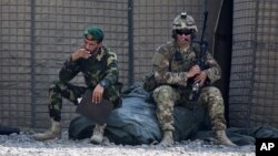 یک سرباز ارتش افغانستان که در کنار یک نظامی آمریکایی نشسته است.