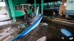 Los pescadores miran los botes parcialmente sumergidos en el agua después de que el huracán Julia azotara el área en Bluefields, Nicaragua, el domingo 9 de octubre de 2022. (AP Foto/Inti Ocon)
