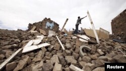 A youth throws a plank of wood away from a pile of rubble of a house destroyed during an air strike carried out by the Saudi-led coalition in Faj Attan village, Sanaa, Yemen, May 7, 2015.
