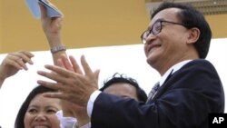 Opposition party leader Sam Raisy, right, claps in front of the National Assembly in Phnom Penh, file photo.