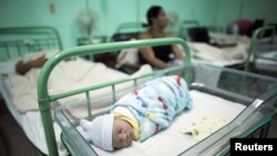 ARCHIVO - Un recién nacido duerme cerca de su madre en un hospital de Camaguey, Cuba, junio 19, 2015. Ese mes, la Organización Mundial de la Salud declaró a Cuba el primer país del mundo en elimininar la transmisión de VIH y sífilis de madre a hijo.