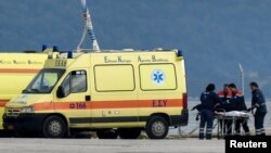 Medical staffers push the body of a migrant into an ambulance at the port of Preveza, Greece, Jan. 11, 2020.