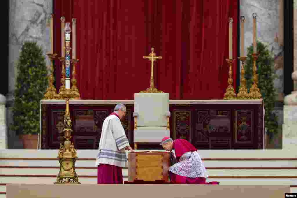 Archbishop Georg Gaenswein, right, kisses the Book of the Gospels on top of former Pope Benedict's coffin during his funeral, in St. Peter's Square at the Vatican, Jan. 5, 2023. 