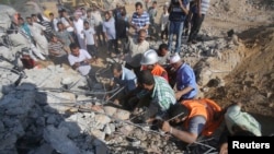 FILE - Palestinians search for victims under the rubble of a house which witnesses said was destroyed by an Israeli airstrike, near Khan Younis in the southern Gaza Strip, July 24, 2014.