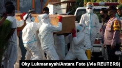 Para petugas mengenakan alat pelindung diri (APD) memakamkan jenazah pasien yang meninggal akibat COVID-19, di Tegal, Jawa Tengah, Rabu, 30 Juni 2021. (Foto: Oky Lukmansyah/Antara Foto via Reuters)