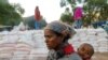 FILE - A woman carries an infant as she waits in line for food, at the Tsehaye primary school, which was turned into a temporary shelter for people displaced by conflict, in the town of Shire, Tigray region, Ethiopia, March 15, 2021.