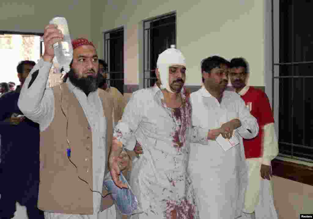 A man who was injured after an explosion in a Shi'ite mosque walks with relatives after receiving medical treatment at a hospital in Shikarpur, Sindh province, Pakistan, Jan. 30, 2015.