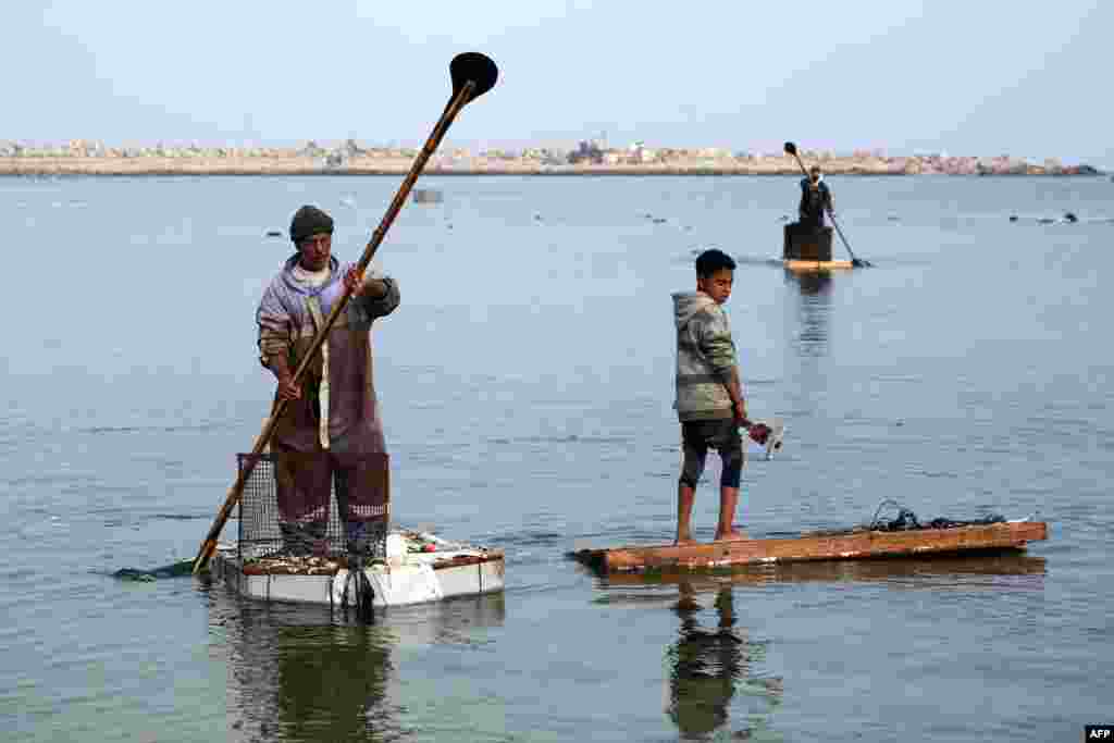 A Palestinian men use the doors of refrigerators as makeshift rowing boats to catch fish at the port of Gaza City, March 9, 2025.